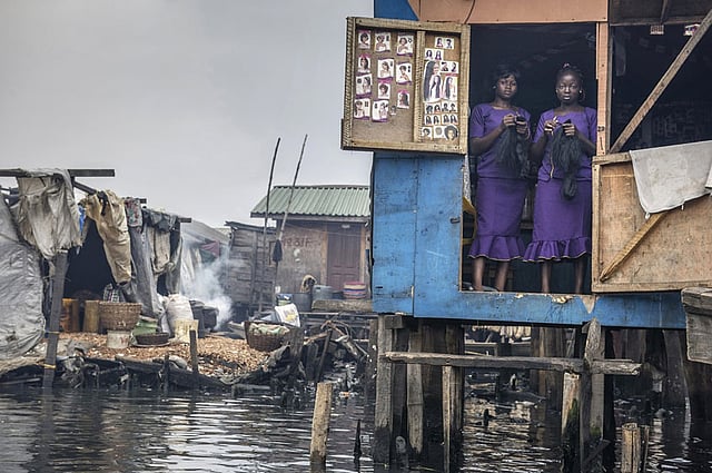 রূপের স্যালুন। লাগোস, ২০১৪। লাগোস লেগুনের দূষিত জলের ওপর গড়ে ওঠা মাকাকো বস্তির এক রূপচর্চা স্যালুন। রোববার বা ছুটির দিনগুলোতে নারীদের সাজগোজের জন্য এসব স্যালুনের ব্যস্ততা বেড়ে যায়। যদিও পুরো মাকাকো বস্তিটাই উচ্ছেদের হুমকির মুখে আছে। আলোকচিত্রী: পেট্টুট কালিনেসকু, নাইজেরিয়া। ছবি: পেট্টুট কালিনেসকু/দ্য অ্যাটকিনস সিআইডব্লিউইএম এনভায়রনমেন্টাল ফটোগ্রাফার অব দ্য ইয়ার
