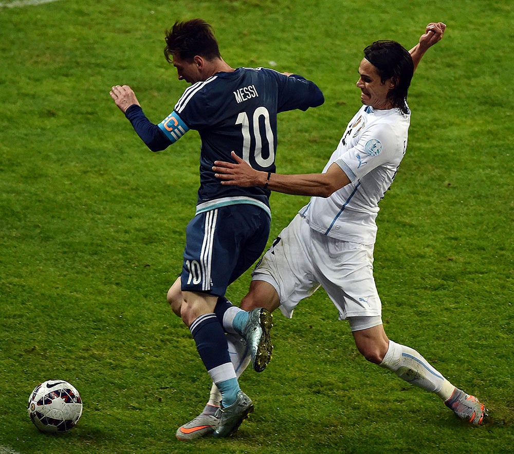 মেসির আরও একটি প্রচেষ্টা। পেছন থেকে বাধা দিচ্ছেন উরুগুয়ের এডিনসন কাভানি। ছবি: এএফপি।
