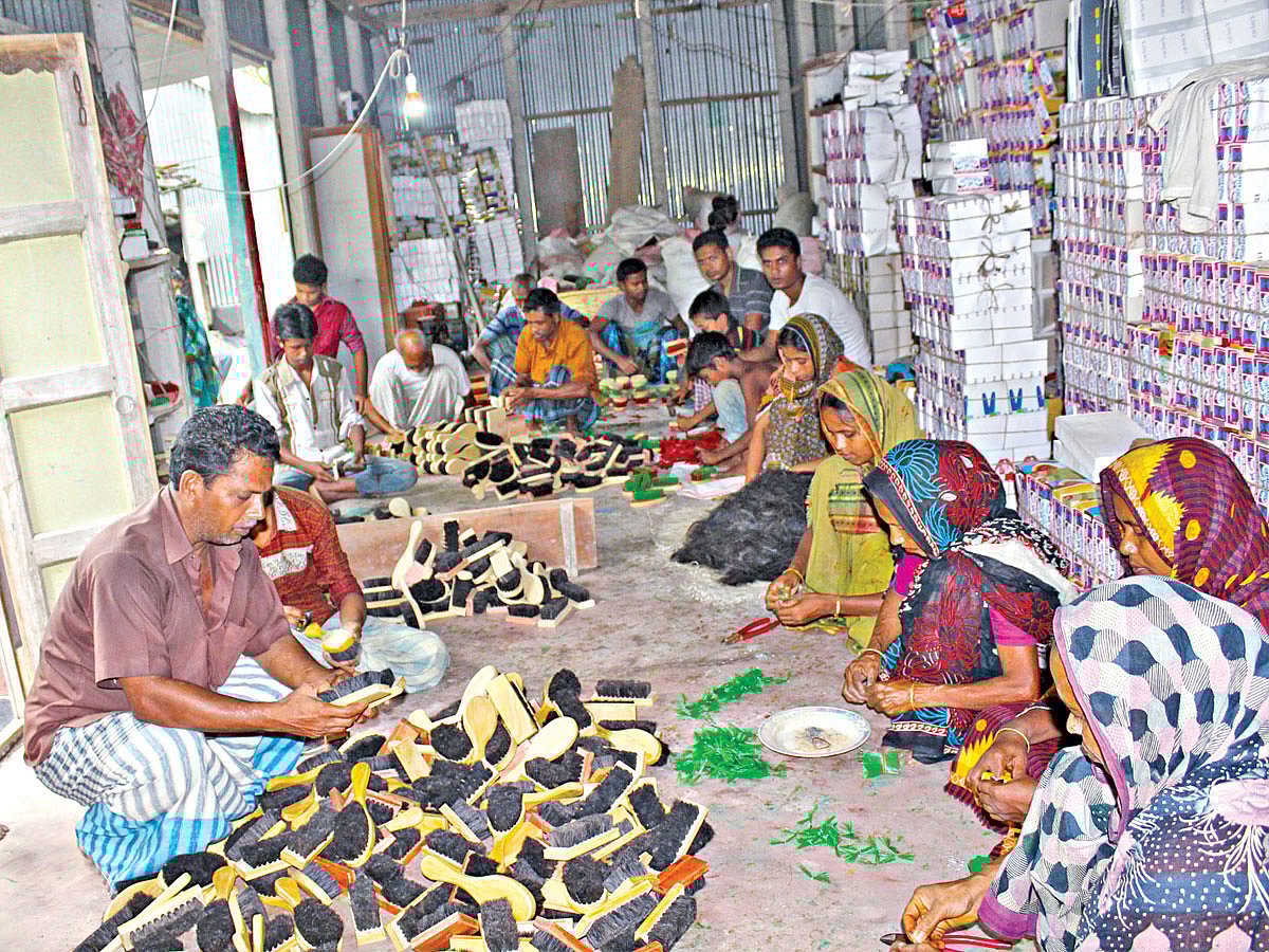 টাঙ্গাইলের দেলদুয়ার উপজেলার হেরেন্দ্রপাড়ায় রমজান আলীর (বাঁয়ে) কারখানায় ব্রাশ তৈরিতে ব্যস্ত কারিগরেরা l ছবি: প্রথম আলো