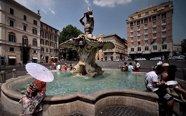 রোমে ঝরনার পাশে বসে আছেন পর্যটকেরা। ছবি: এএফপি