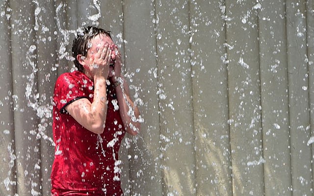 কৃত্রিম ঝরনার নিচে দাঁড়িয়ে নিজিকে জিরিয়ে নিচ্ছেন এক পর্যটক। ছবিটি ইতালির মিলান শহর থেকে তোলা। ছবি: এএফপি