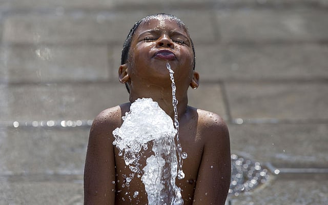 একটু স্বস্তির জন্য কৃত্রিম ঝরনায় দাঁড়িয়ে আছে শিশুটি। ছবিটি বেলজিয়ামের ব্রাসেলস থেকে তোলা। ছবি: রয়টার্স
