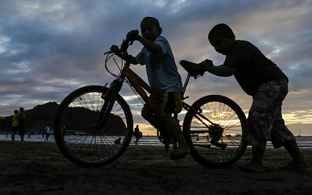 নিকারাগুয়ার রিভাসের সান হুয়ান দেল সুরের একটি সৈকতে সন্ধ্যায় সাইকেল নিয়ে খেলছে দুই শিশু। ছবি: এএফপি