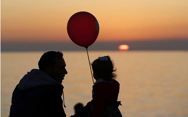 ফিলিস্তিনের গাজায় সূর্যাস্তের সময় মেয়েকে নিয়ে খেলছেন এক বাবা। ছবি: এএফপি