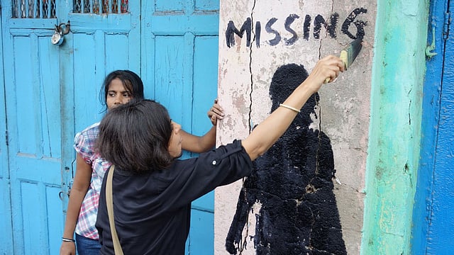 একটা সিল্যুট আঁকার পর তাতে মিসিং কথাটি লিখে দিচ্ছেন শিল্পী লীনা কেজরিওয়াল নিজেই। ছবি: দ্য গার্ডিয়ান।