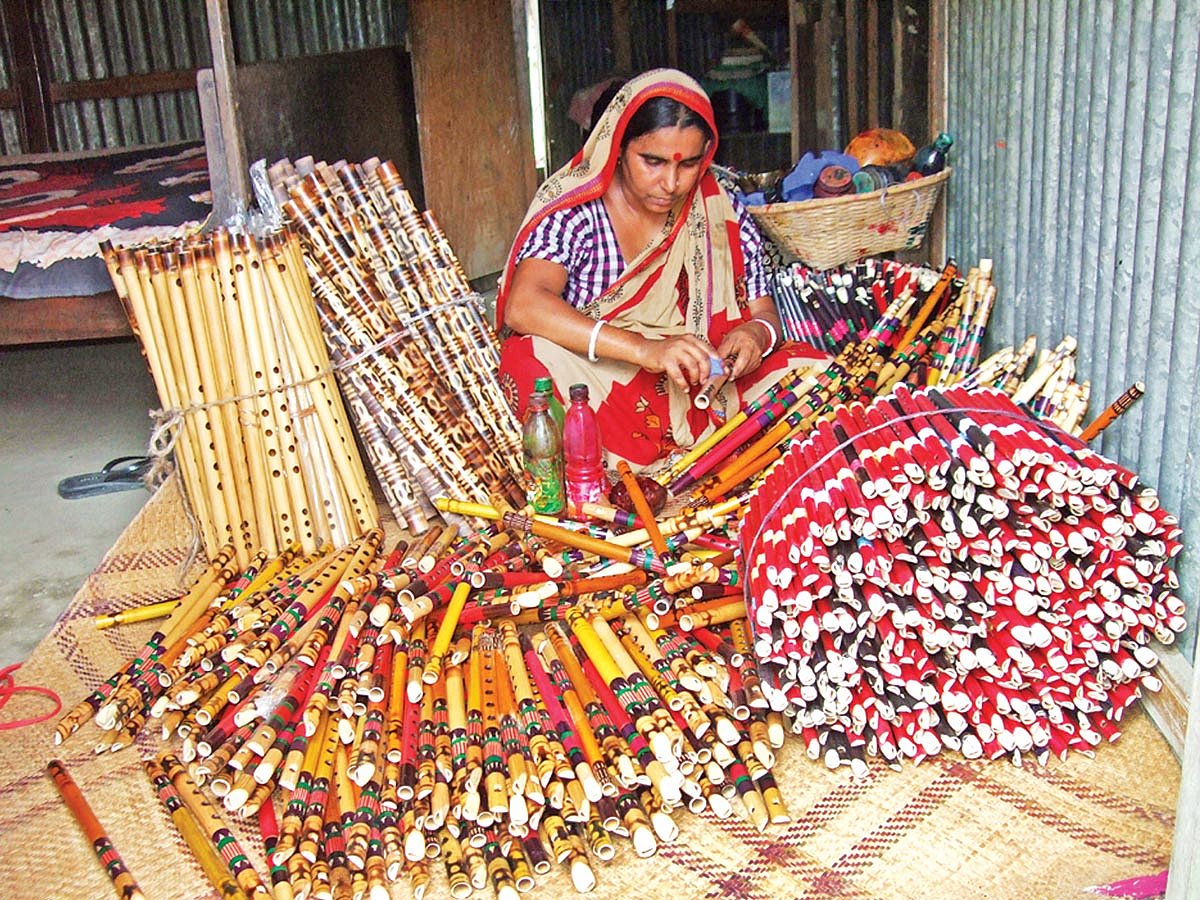 কুমিল্লার হোমনা উপজেলার শ্রীমদ্দী গ্রামে রং দিয়ে বাঁশিতে নকশা ফুটিয়ে তোলার কাজে ব্যস্ত এক নারী l ছবি: প্রথম আলো