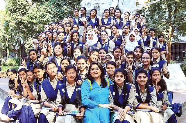 ঢাকা বিশ্ববিদ্যালয়ে অপরাজেয় বাংলার পাদদেশে স্বর্ণ কিশোরী নেটওয়ার্ক ফাউন্ডেশনের সভাপতি ফারজানা ব্রাউনিয়ার সঙ্গে কিশোরীরা। ছবি: অধুনা