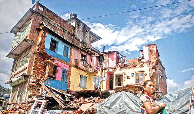 নেপালে এপ্রিল মাসের ভয়াবহ ভূমিকম্পের শিকার একটি বাড়ির সামনে দাঁড়িয়ে এক হতবিহ্বল নারী l এএফপি