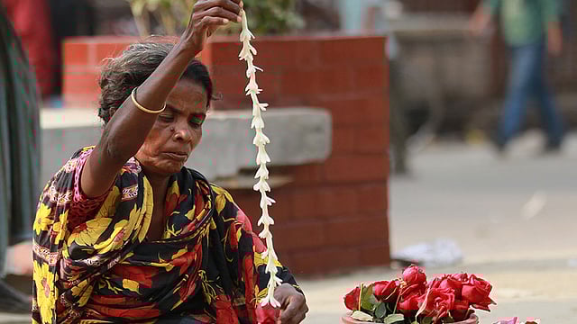 রাজধানীর শাহবাগ এলাকায় ফুলের মালা তৈরি করছেন এক নারী। মালা বিক্রি করেই জীবিকা নির্বাহ করেন তিনি। ছবি: শামসুল হক