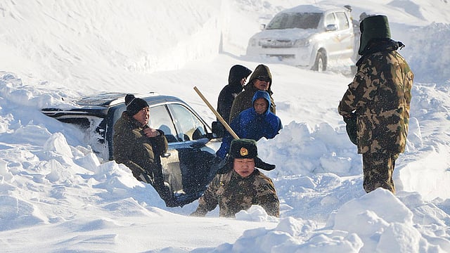 চীনের স্বায়ত্তশাসিত অঞ্চল জিনঝিয়াং উইঘুরের আলতে এলাকায় বরফে আটকা পড়া একটি গাড়িকে উদ্ধারের চেষ্টা করছে পুলিশ। ছবিটি ৩ ​জানুয়ারি তোলা। ছবি: রয়টার্স