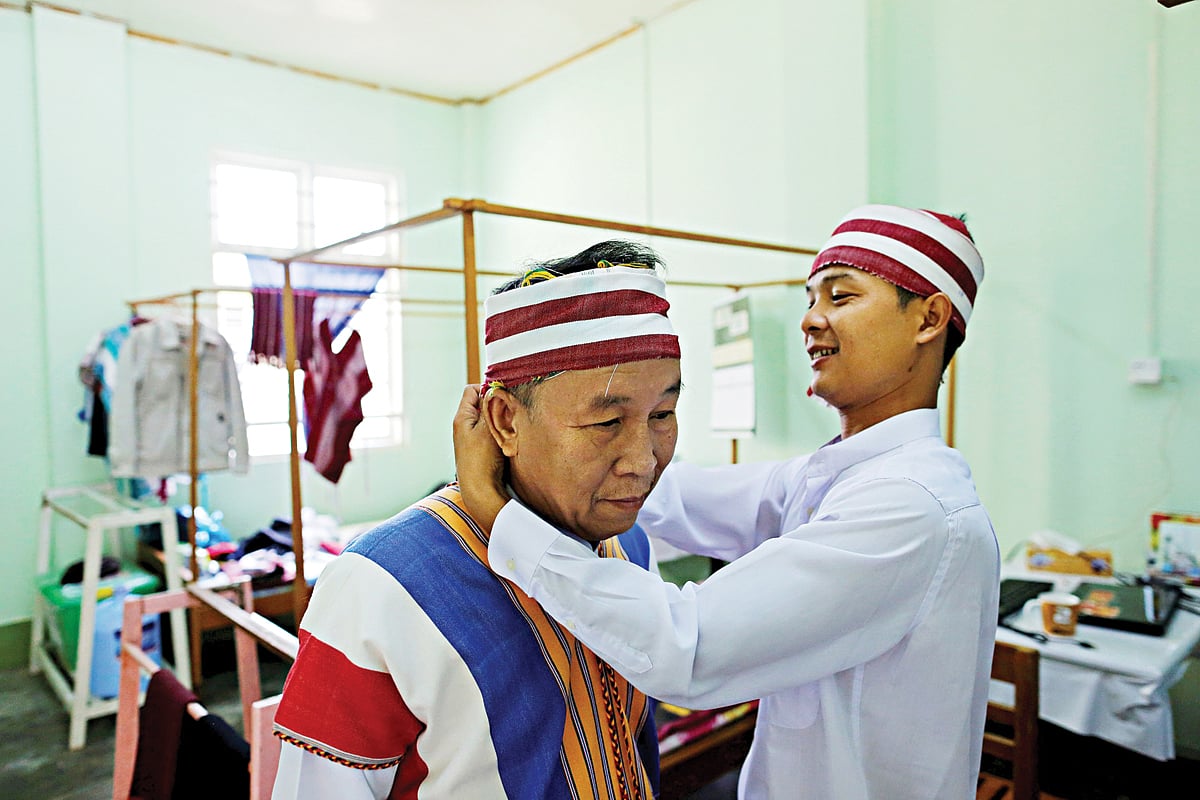 পার্লামেন্টের উচ্চকক্ষে যোগ দেওয়ার আগে এনএলডির নবনির্বাচিত একজন সদস্য আরেকজনকে ঐতিহ্যবাহী পোশাক পরতে সাহায্য করছেন। বুধবারের ছবি l রয়টার্স