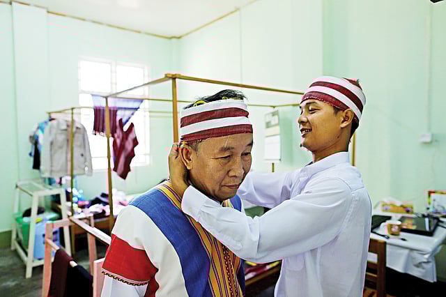 পার্লামেন্টের উচ্চকক্ষে যোগ দেওয়ার আগে এনএলডির নবনির্বাচিত একজন সদস্য আরেকজনকে ঐতিহ্যবাহী পোশাক পরতে সাহায্য করছেন। বুধবারের ছবি l রয়টার্স