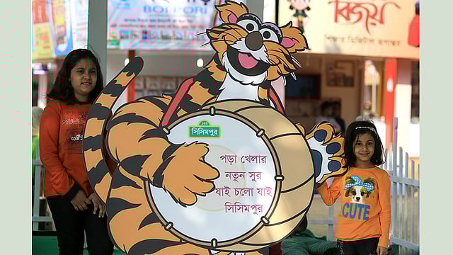 বইমেলায় রাখা সিসিমপুরের কার্টুন চরিত্রের পাশে দাঁড়িয়ে ছবি তুলছে দুই শিশু। ছবি: আশরাফুল আলম
