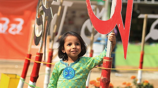 বইমেলায় বাংলা একাডেমির বর্ণমালার সামনে দাঁড়িয়ে ছবি তুলছে শিশুটি। ছবি: আশরাফুল আলম