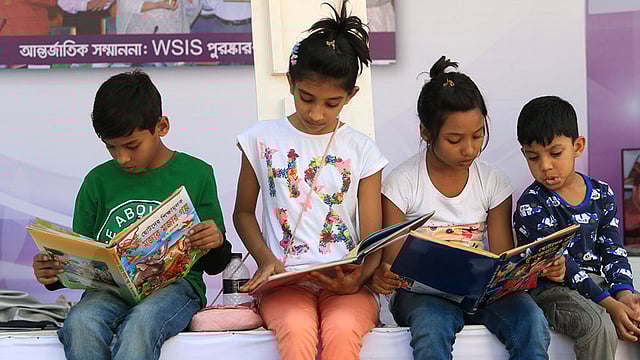 কিনে নেওয়া বই মেলায় বসেই পড়ছে খুদে পাঠকেরা। ছবি: আশরাফুল আলম