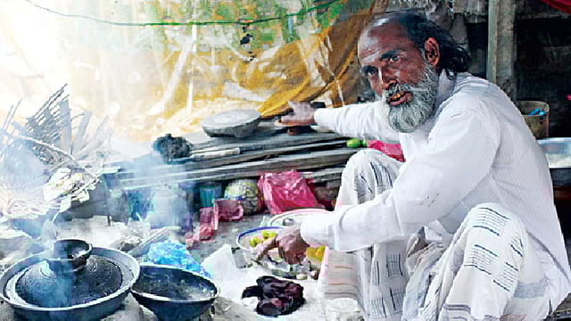 কবরের ওপরে চুলায় চলছে রান্না। পাশে আরেকটি কবর দেখাচ্ছেন আবুল হোসেন l প্রথম আলো