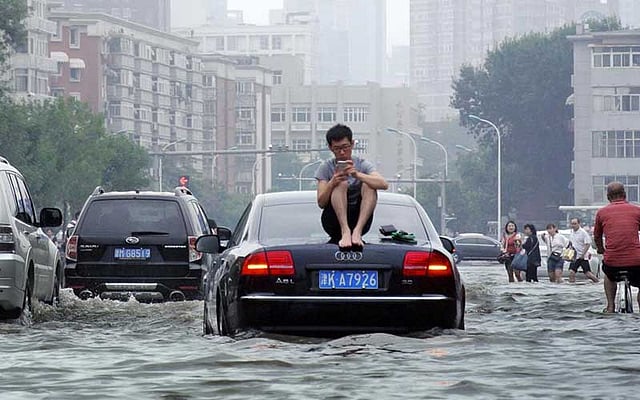 বন্যার পানিতে সড়ক ডুবে গেছে। কী আর করা? অগত্যা গাড়ির পিঠে সওয়ার। ছবিটি গতকাল বৃহস্পতিবার চীনের তিয়ানজিন থেকে তোলা। ছবি: রয়টার্স