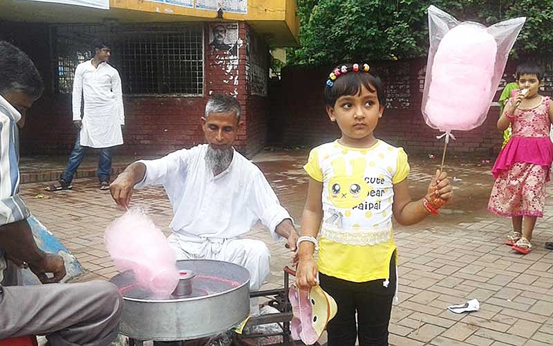 শিশু পার্কের সামনে হাওয়াই মিঠাই বানাচ্ছেন ইসমাইল হোসেন। ছবি: প্রথম আলো