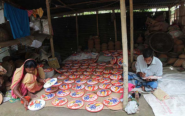 শারদীয় দুর্গাপূজা শেষে আগামী শনিবার লক্ষ্মীপূজা। পূজায় দরকার হয় মাটির তৈরি সরা (লক্ষ্মীরসরা)। দুর্গাপূজার বিসর্জন ঘাটে বসবে মেলা। মেলায় লক্ষ্মীরসরা বিক্রির জন্য ফরিদপুর সদর উপজেলার হাড়োকান্দি পালপাড়া এলাকায় অমল চন্দ্র পাল স্ত্রী মালতি রানী পালকে সঙ্গে নিয়ে সরায় রঙের আঁচড় দিচ্ছেন। ছবিটি সোমবার সকালে তোলা। ছবি: আলীমুজ্জামান
