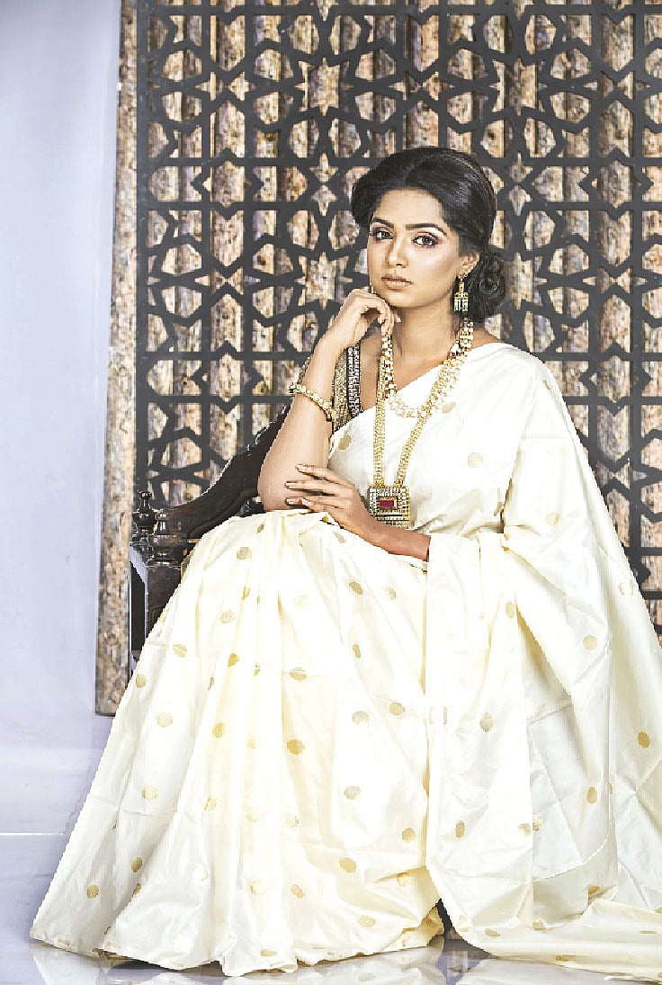 হালকা নকশায় সাদা শাড়িতে স্নিগ্ধ আমেজ। গলায় মুক্তা ও কুন্দনের গয়না পড়েছেন মডেল হিমি। গলায় ভারী গয়না, এ কারণে কানে হালকা নকশার দুল