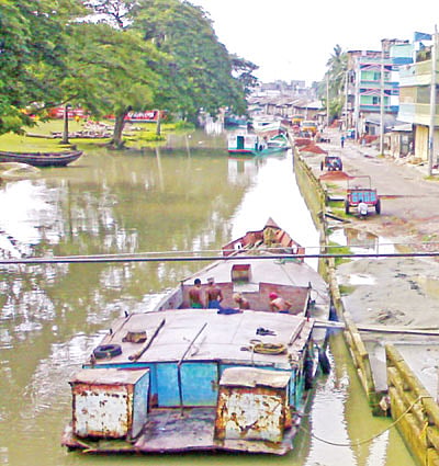 ধান–চালের আড়তের সামনে​ ভোলা খালে পণ্যবাহী নৌযান। খালের অন্য পাশে ভোলা সরকারি বালক উচ্চবিদ্যালয়। সম্প্রতি তোলা ছবি l প্রথম আলো