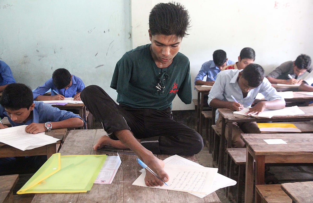 দুটি হাত নেই। তারপরও পা দিয়ে লিখেই জেএসসি পরীক্ষায় বি গ্রেড পেয়ে পাস করেছে জসীম মাতুব্বর। ছবিটি জেএসসি পরীক্ষার সময় তোলা। ছবি:আলীমুজ্জামান