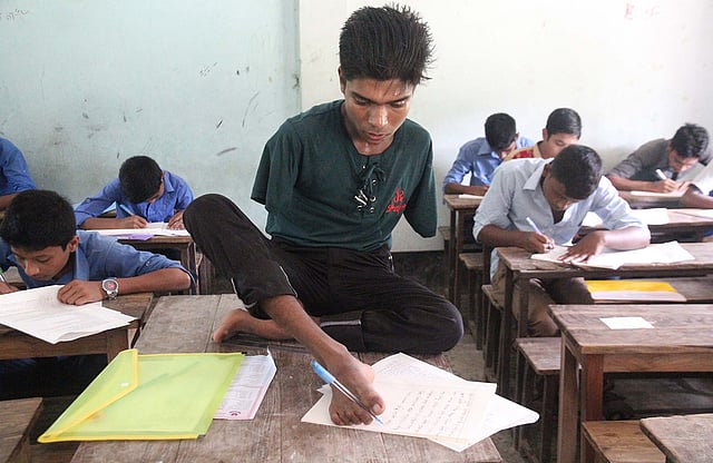 দুটি হাত নেই। তারপরও পা দিয়ে লিখেই জেএসসি পরীক্ষায় বি গ্রেড পেয়ে পাস করেছে জসীম মাতুব্বর। ছবিটি জেএসসি পরীক্ষার সময় তোলা। ছবি:আলীমুজ্জামান