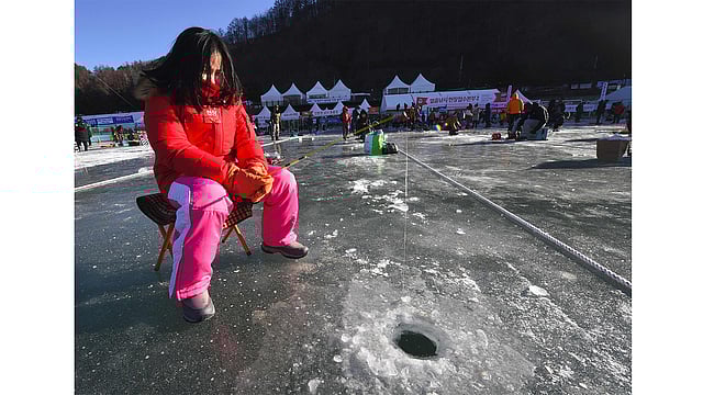 গর্তে বড়শি ফেলে মাছের অপেক্ষায়। ছবি: এএফপি