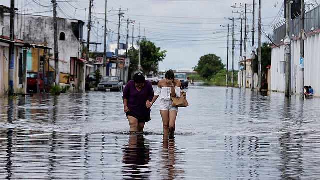 ইকুয়েডরের ডুরানে বৃষ্টিতে ভেসে গেছে রাস্তা। পানি ভেঙে হেঁটে যাচ্ছেন দুজন। ছবিটি মঙ্গলবারের। ছবি: রয়টার্স