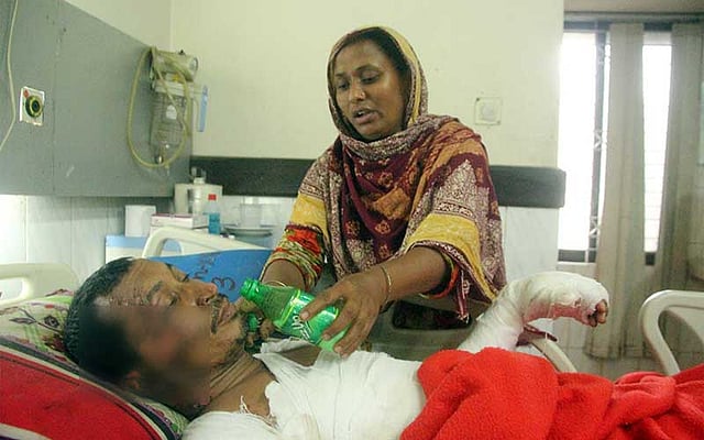 দিনাজপুরে বয়লার বিস্ফোরণে দগ্ধ বাদল ইসলাম রংপুর মেডিকেল কলেজ হাসপাতালের বার্ন ইউনিটে চিকিৎসাধীন। স্ত্রী রোকসানা তাঁর মুখে পানি তুলে দিচ্ছেন। এই বিস্ফোরণেই বাদলের তিন ভাই মারা গেছেন। ছবি: মঈনুল ইসলাম