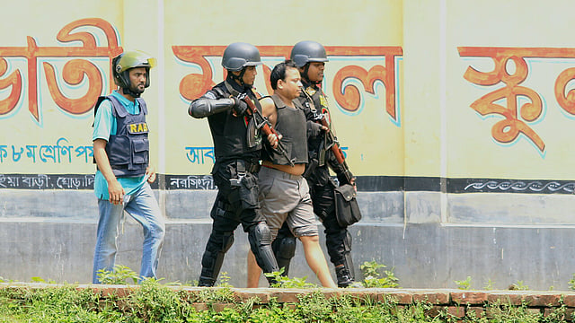 নরসিংদীতে গাবতলীর উত্তরপাড়ার সন্দেহভাজন জঙ্গি আস্তানা থেকে একজনকে বের করে নিয়ে যাচ্ছেন র‍্যাবের সদস্যরা। ছবিটি রোববার সকালে তোলা। ছবি: আশরাফুল আলম