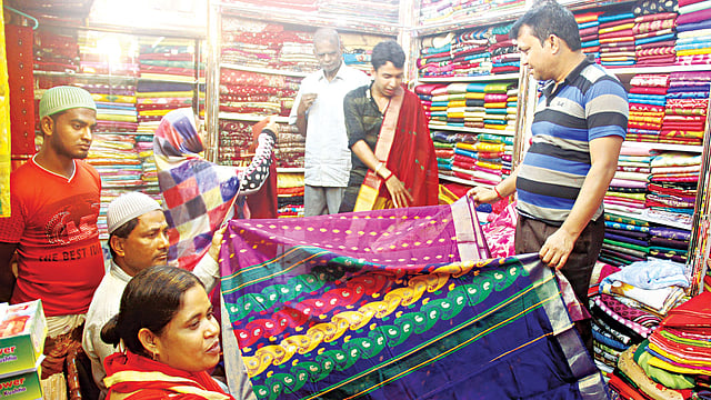 কুষ্টিয়ার বাজারে এবার শাড়ি বিক্রি কমেছে। তারপরও পরিবারের সদস্যদের জন্য দু–একটা শাড়ি কিনছেন কেউ কেউ। ছবিটি গতকাল শহরের লাভলী টাওয়ার শপিংমল থেকে তোলা l প্রথম আলো