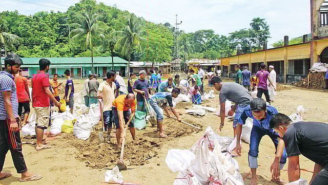 পাহাড়ি ঢলের সঙ্গে আসা বালুর নিচে হারিয়ে গেছে রাঙামাটির কাউখালীর ঘাগড়া উচ্চবিদ্যালয় মাঠ। অভিভাবক ও শিক্ষক–শিক্ষার্থীরা গতকাল সকাল থেকে স্বেচ্ছাশ্রমে বালু তুলে মাঠ পরিষ্কারের কাজ করেন l ছবি: প্রথম আলো