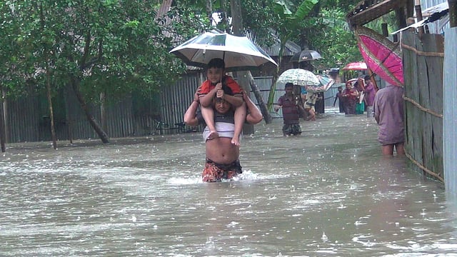 পৌরসভার খালপাড়া এলাকা থেকে আশ্রয়কেন্দ্রে ছুটছে পানিবন্দী মানুষ। গতকালের ছবি l প্রথম আলো