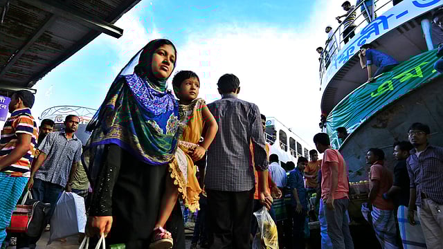 শিশুকে কোলে নিয়ে নির্দিষ্ট লঞ্চের খোঁজে এক নারী যাত্রী। ছবিটি বিকেলে তোলা। ছবি: হাসান রাজা