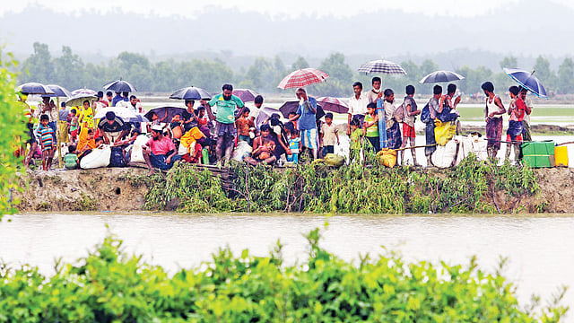 রাখাইন রাজ্য থেকে প্রাণভয়ে পালিয়ে আসা একদল রোহিঙ্গা গতকাল বাংলাদেশে ঢুকেছে। টেকনাফের হোয়াইক্যংয়ের লম্বাবিল খালের ওপারে নৌকার জন্য অপেক্ষা করছে তারা l ছবি: আশরাফুল আলম