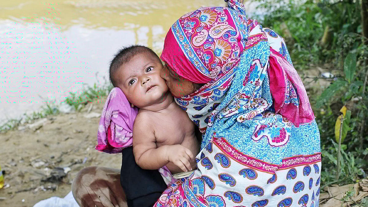 গরমে অতিষ্ঠ এক রোহিঙ্গা নারী তাঁর সন্তানকে গাছের ছায়ায় আদর করছেন। ছবিটি গতকাল সকালে টেকনাফের তাজনিমারঘোনার অস্থায়ী আশ্রয় শিবির থেকে তোলা l সাবিনা ইয়াসমিন