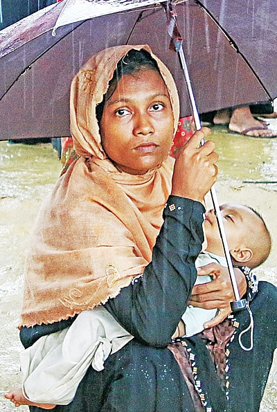 বৃষ্টি উপেক্ষা করে কোলে শিশু নিয়ে ত্রাণ নিতে এসেছেন এক মা। ছবিটি গতকাল বিকেলে উখিয়ার থাইংখালী থেকে তোলা l প্রথম আলো