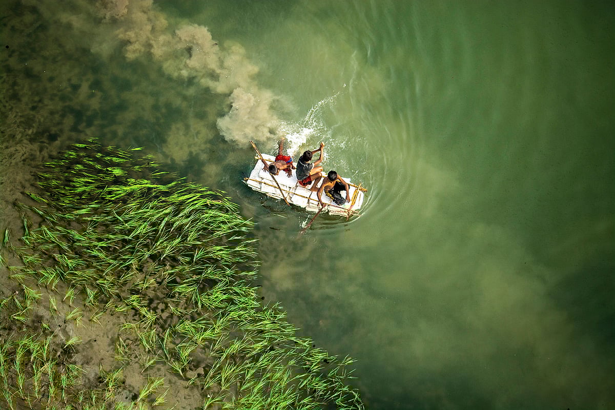 নদীতে ভেলা ভাসিয়েছে তিন দুরন্ত শিশু। তরা সেতু, মানিকগঞ্জ। ছবি: অপু জামান