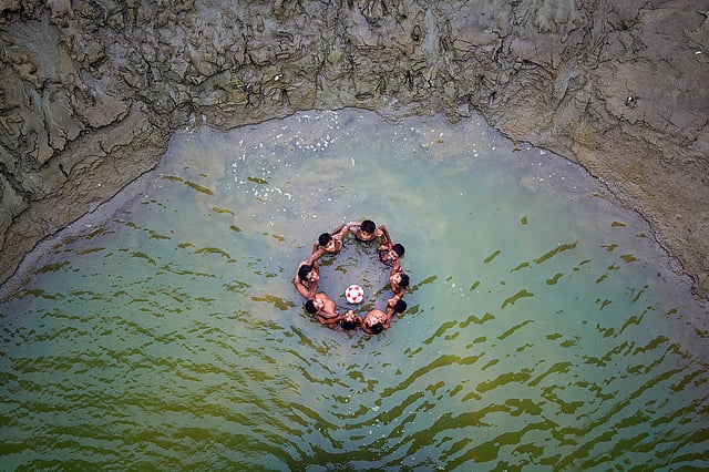 দল বেঁধে পানিতে ফুটবল খেলা। তরা সেতু, মানিকগঞ্জ। ছবি: অপু জামান