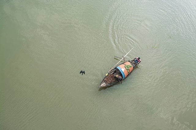 নৌকা বেয়ে যাচ্ছে মাঝি। মহানন্দা সেতু, চাঁপাইনবাবগঞ্জ। ছবি: অপু জামান