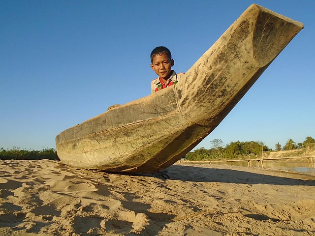 খাগড়াছড়ির চেঙ্গি নদীতে ভেসে উঠেছে চর। চরে পড়ে আছে নৌকা। সে নৌকায় খেলছে এক পাহাড়ি শিশু। বেলতলীপাড়া, খাগড়াছড়ি সদর, ৩১ ডিসেম্বর। ছবি: নীরব চৌধুরী