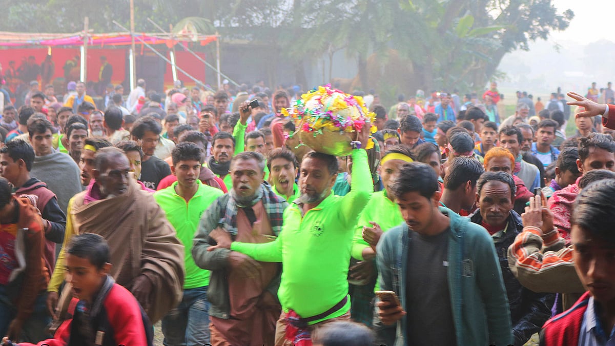মাথায় হুমঘুঁটি নিয়ে দৌড়াচ্ছেন একজন। গতকাল ময়মনসিংহের ফুলবাড়িয়া উপজেলার আটা গ্রামে l প্রথম আলো
