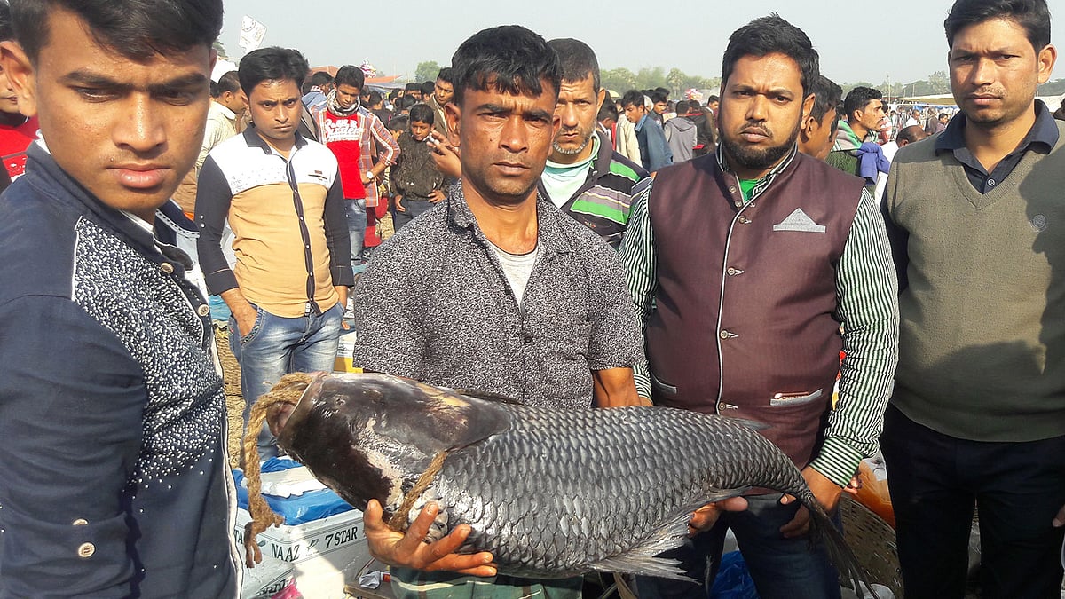 কালীগঞ্জের বিনিরাইল গ্রামে মেলায় মাছ হাতে এক িবক্রেতা
