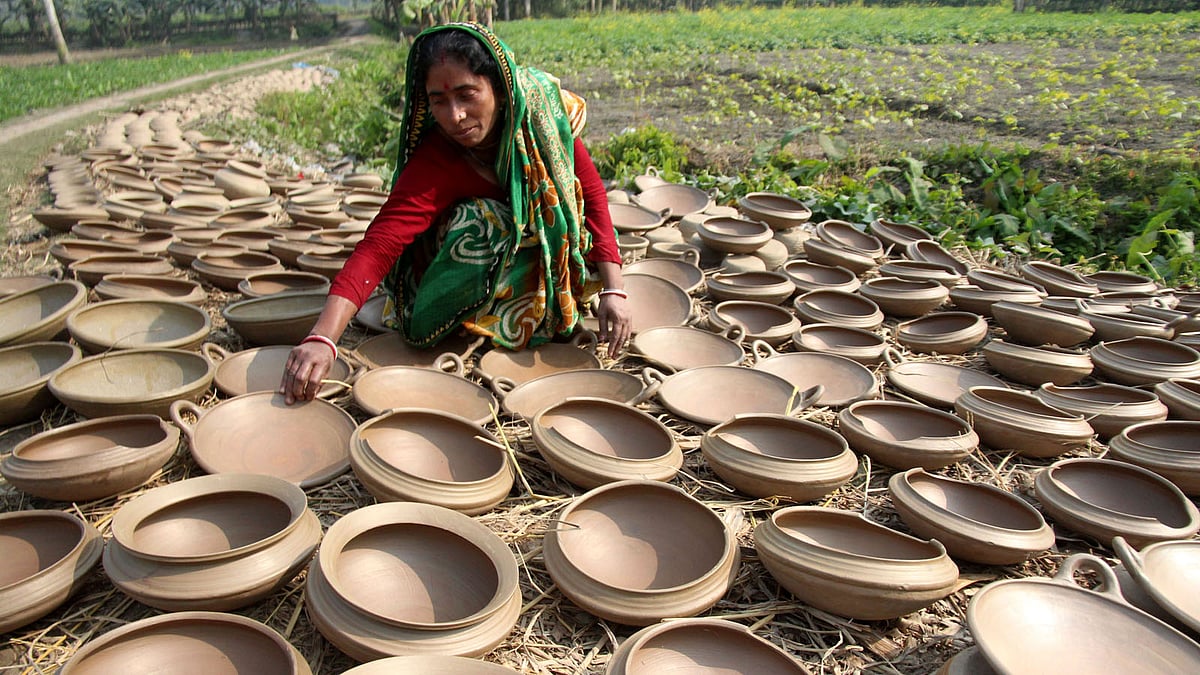 পিঠা তৈরির মাটির ‘কাটা খোলা’ রোদে শুকাতে দিচ্ছেন একজন।