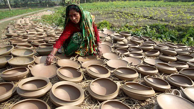পিঠা তৈরির মাটির ‘কাটা খোলা’ রোদে শুকাতে দিচ্ছেন একজন।
