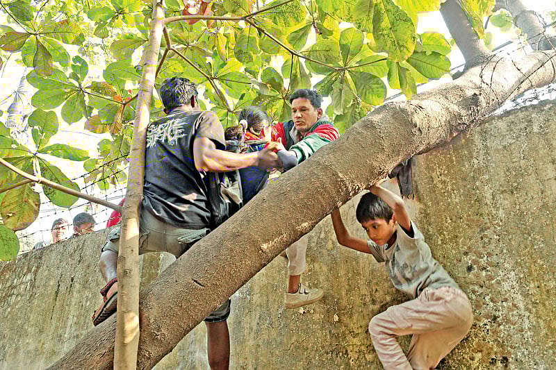 স্কুল ভবনের ভেতরে তালাবদ্ধ স্মৃতি মণি ও মণি দে নামের তৃতীয় শ্রেণির দুই ছাত্রীকে উদ্ধার করে দেয়ালের ওপর দিয়ে পার করে দিচ্ছেন স্থানীয় লোকজন। গতকাল বেলা তিনটায় চট্টগ্রামের সরকারি ন্যাশনাল প্রাইমারি স্কুলে l প্রথম আলো
