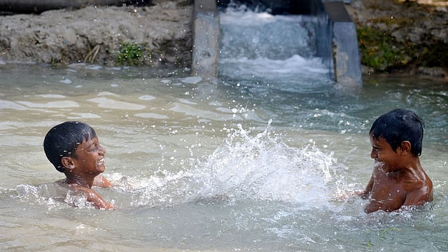 সেচ পাম্প থেকে বের হচ্ছে পানি। এ শীতেও সেই পানিতে নেমে পড়েছে দুই শিশু। ভবানীপুর, পাবনা সদর, ২৫ জানুয়ারি। ছবি: হাসান মাহমুদ