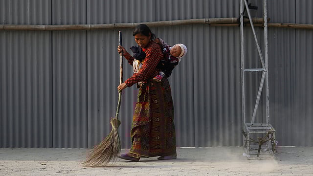 নেপালের ৫০ বছর বয়সী হেরা মায়া তামাংয়ের কাছে অন্যান্য দিনের মতো সাধারণ এই দিনটি। নাতনিকে পিঠে বেঁধে মেঝে ঝাড়ু দিচ্ছেন তিনি। কাঠমান্ডু, নেপাল, ৮ মার্চ। ছবি: রয়টার্স