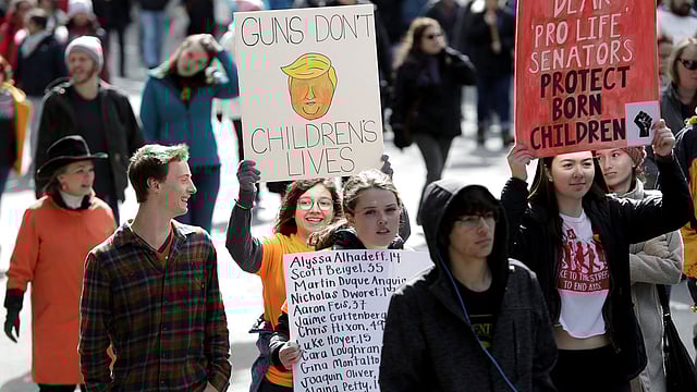 বিভিন্ন প্ল্যাকার্ড নিয়ে র‍্যালিতে জড়ো হয় শিক্ষার্থীরা। ছবি: রয়টার্স